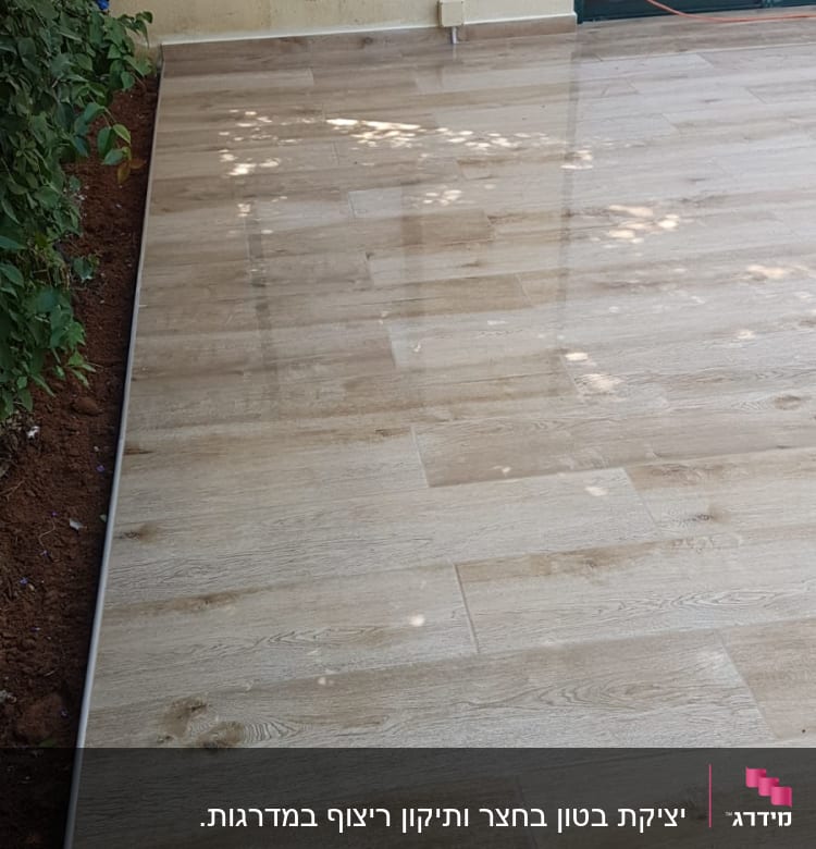 ריצוף חדש מעץ בחצר עם קיר חיצוני